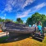 Eksponat, stara drewniana łódź, turysta z dzieckiem w Galerii Rybackiej w Jezierzanach