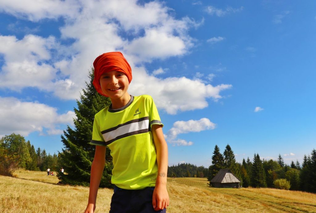 Szczęśliwe, uśmiechnięte dziecko na gorczańskiej polanie, Magurki, letnie i słoneczne popołudnie