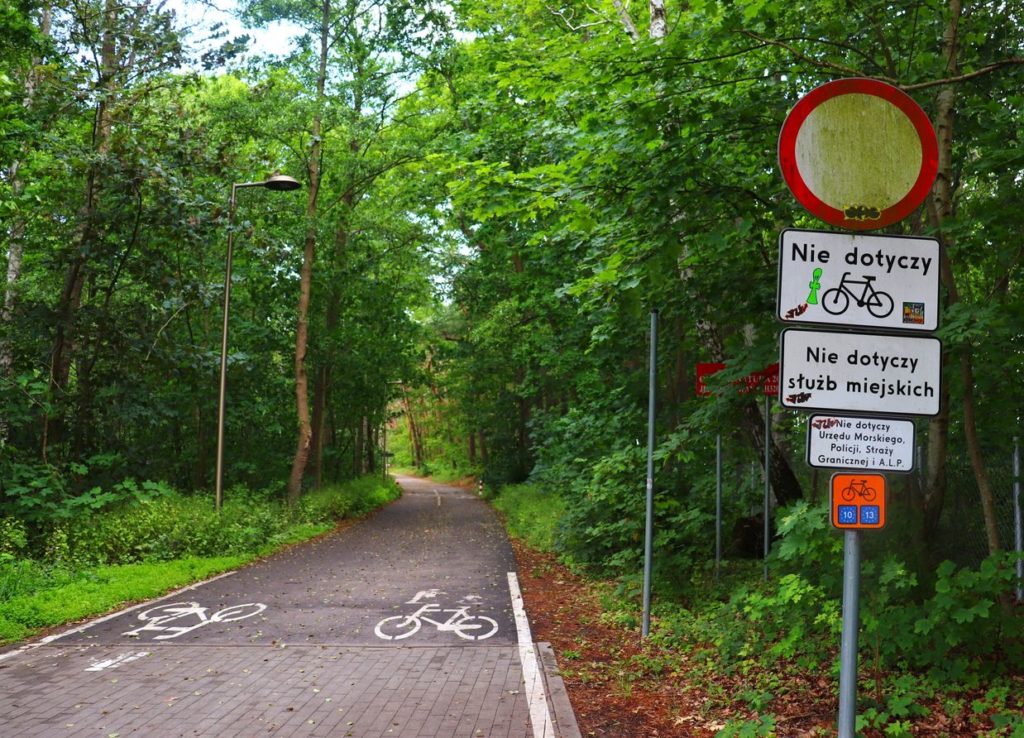 Trasa piesza i szlak rowerowy - Wieś Wicie, szeroka asfaltowa droga prowadząca przez las, zakaz wjazdu samochodów