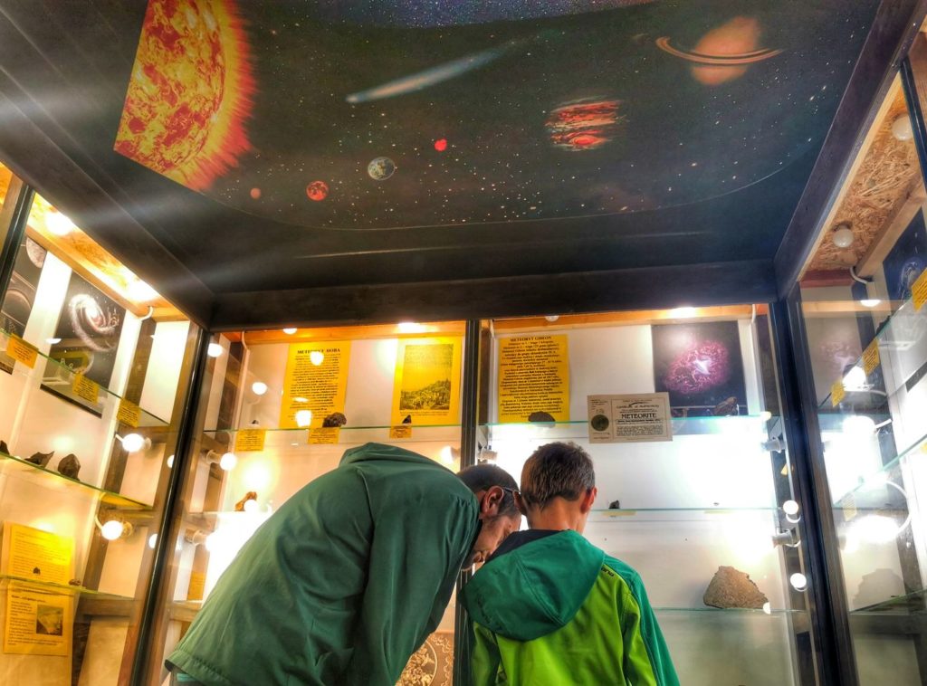 Turysta z dzieckiem w Muzeum Mineralogicznym w Szklarskiej Porębie, sala, w której prezentowane są meteoryty