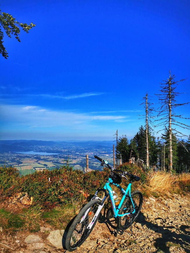 Widok rozciągający się z okolic szczytu Skrzyczne, rower, kamienista droga, błękitne niebo