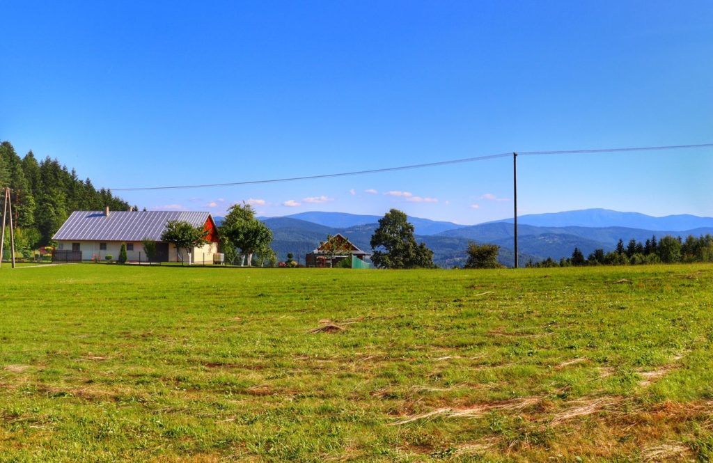 Widok z Przełęczy Carchel w Beskidzie Małym, domki letniskowe, niebieskie niebo