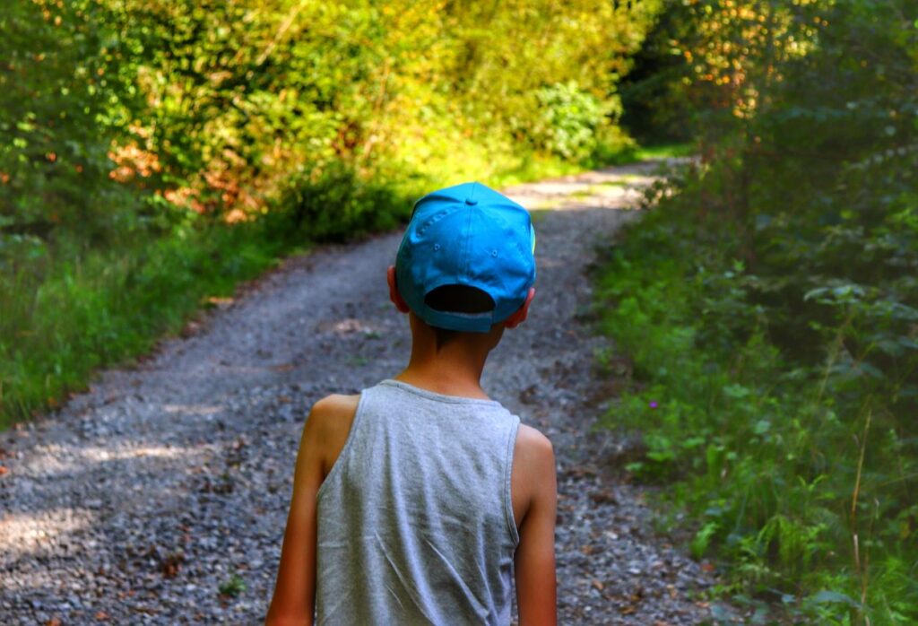 Dziecko idące szeroką leśną drogą na szlaku zielonym w Międzybrodziu Żywieckim