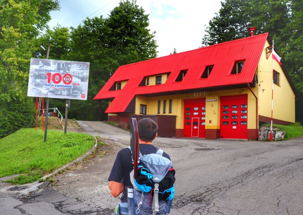 Turysta na czerwonym szlaku w Zwardoniu, budynek OSP w Zwardoniu