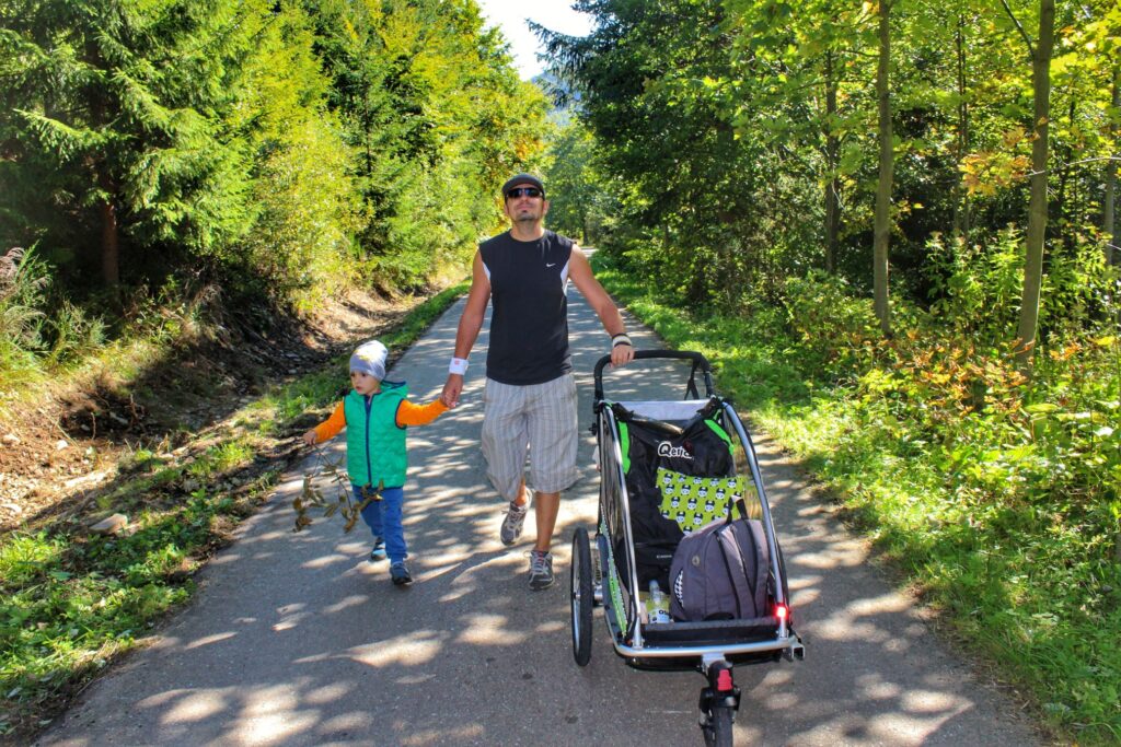 Turysta z dzieckiem, przyczepka rowerowa, szeroka i asfaltowa droga - Dolina Zimnika, szlak żółty