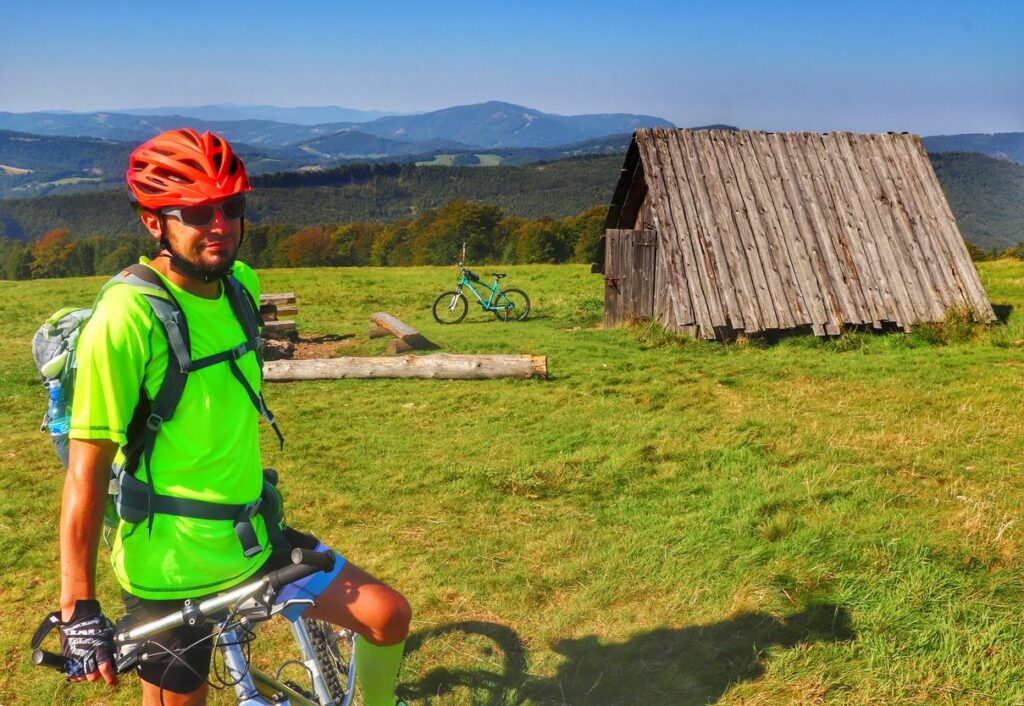 Uśmiechnięty rowerzysta na Hali Jaworowej w Beskidzie Śląskim, w tle drewniany szałas i krajobraz górski