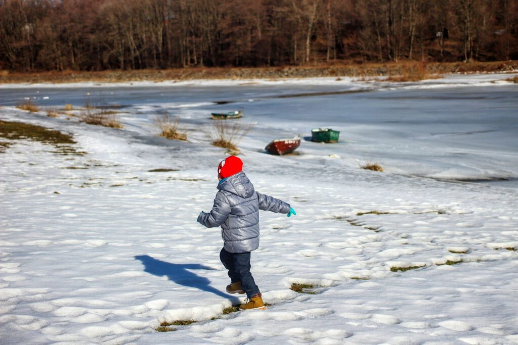 Dziecko biegnące brzegiem Jeziora Żywieckiego, zima
