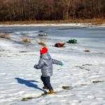 Dziecko biegnące brzegiem Jeziora Żywieckiego, zima