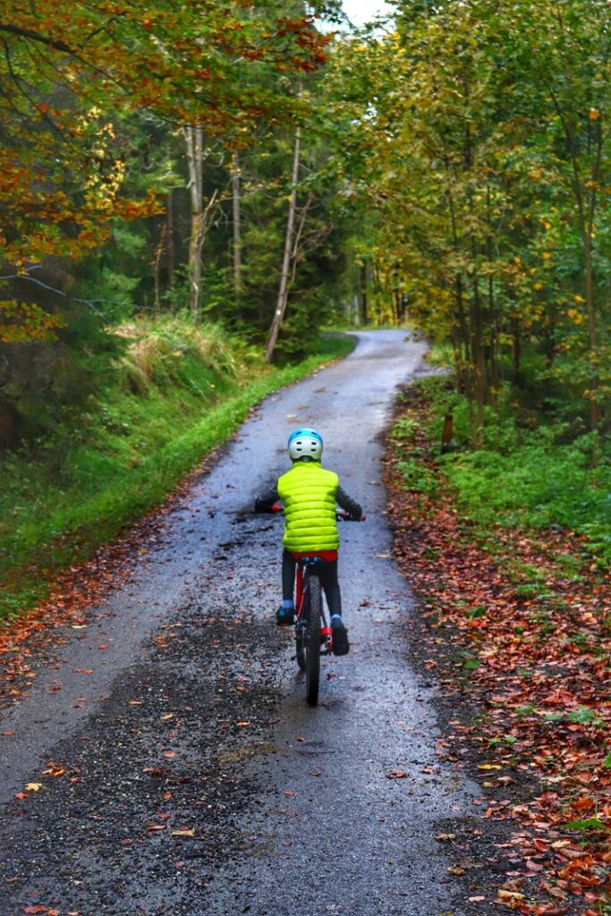 Dziecko jadące drogą prowadzącą przez las, szlak żółty spacerowy w Istebnej, jesień