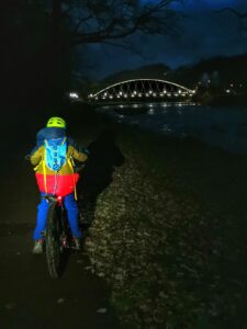 Późny wieczór, dziecko na rowerze, oświetlony most w Żywcu