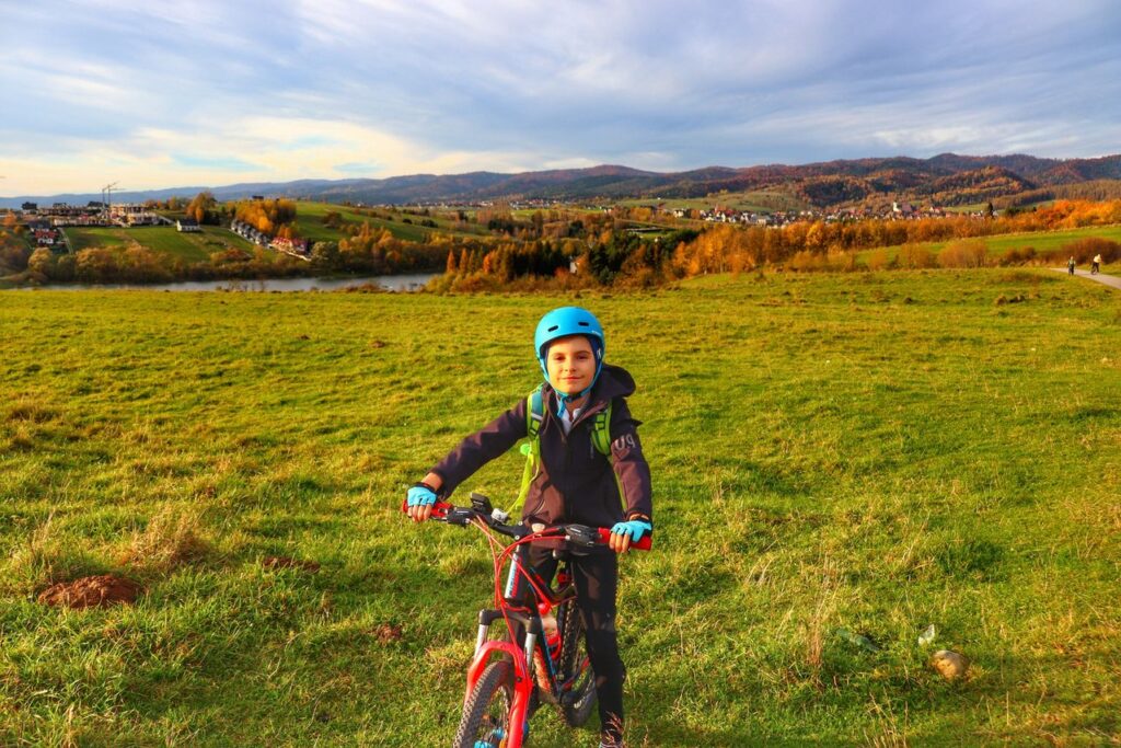 Uśmiechnięte dziecko na rowerze, polana przy szlaku rowerowym Velo Czorsztyn 