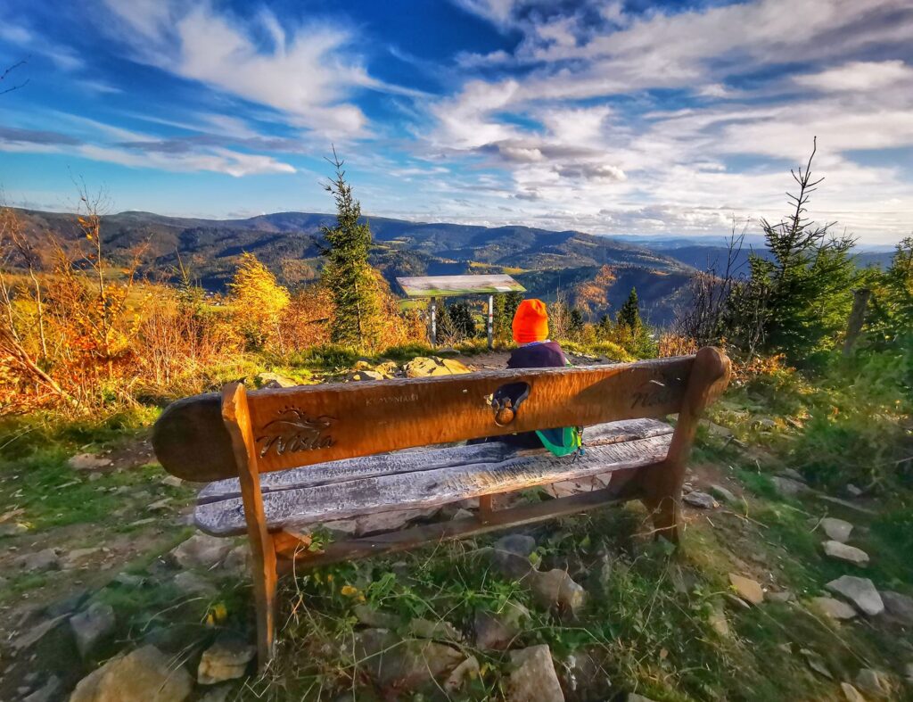 Dziecko odpoczywające na drewnianej ławeczce na szczycie Czupel Wiślański, krajobraz górski 