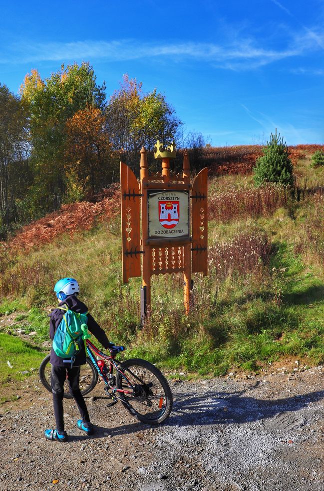 Dziecko na rowerze przy znaku - Gmina Czorsztyn do zobaczenia