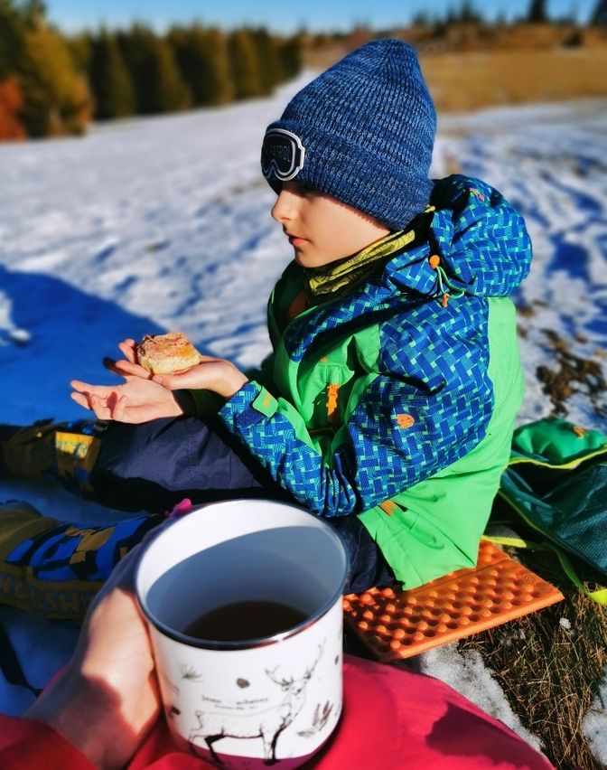 Dziecko odpoczywające na beskidzkiej hali w Korbielowie, kubek z herbatą, bułka - przerwa na posiłek 