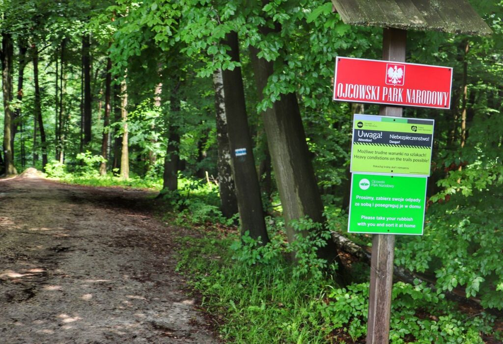 Leśna droga, czerwona tablica z napisem OJCOWSKI PARK NARODOWY, Czajowice szlak niebieski