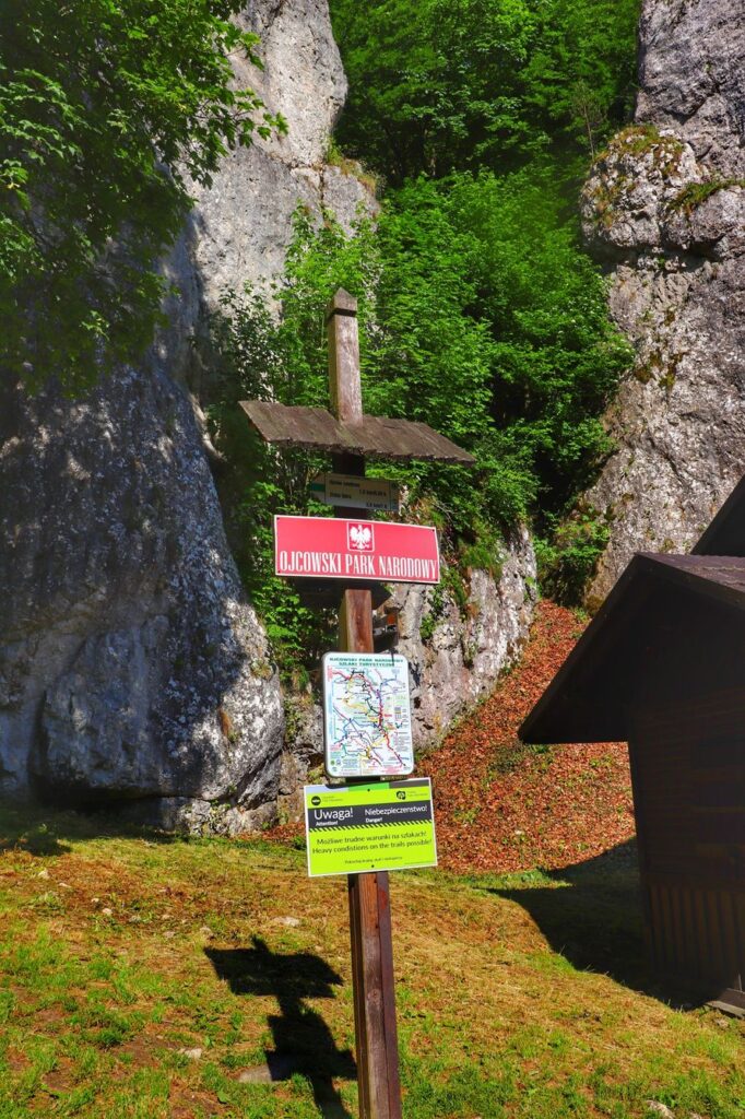 Czerwone tablica z napisem Ojcowski Park Narodowy - okolice Jaskini Ciemnej 