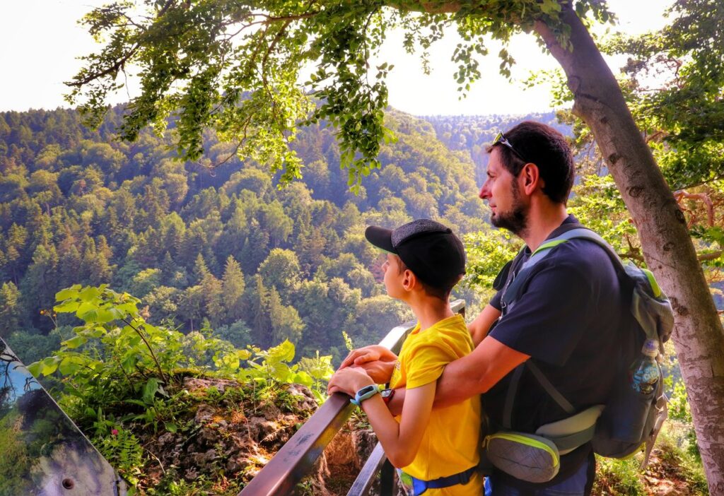 Turysta z dzieckiem podziwiający widoki rozciągające się z Góry Koronnej w Ojcowskim Parku Narodowym 