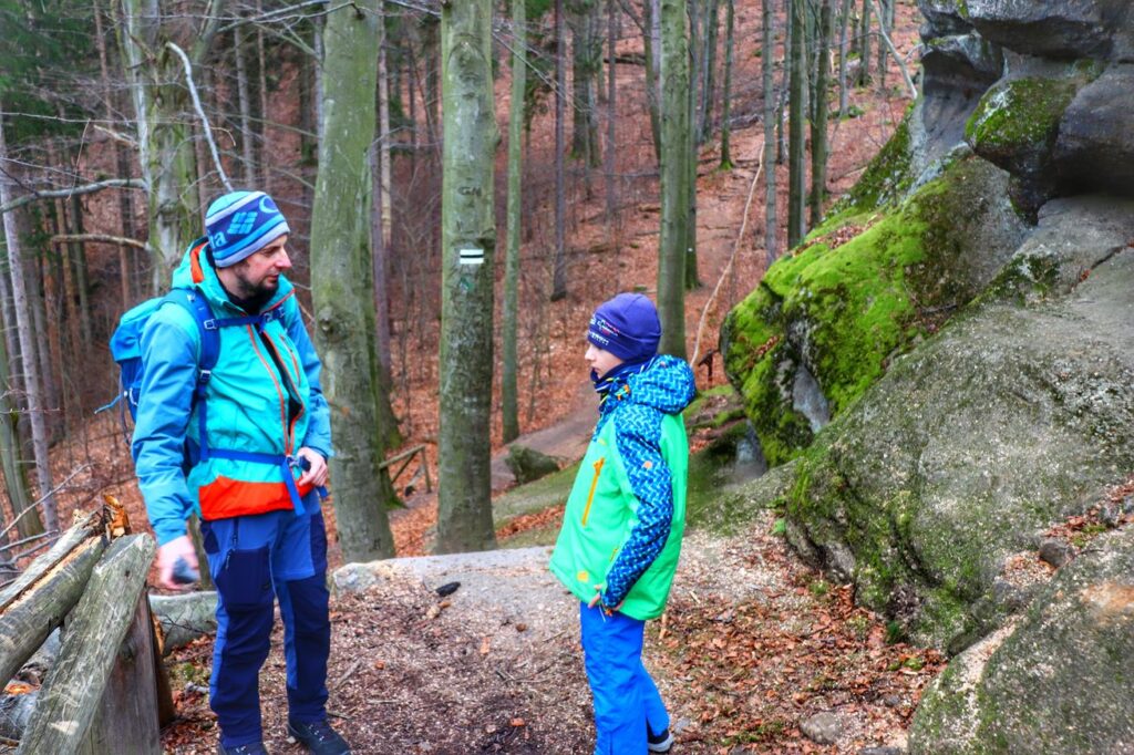 Turysta z dzieckiem na szlaku czarnym prowadzącym przez Zbójeckie Skały do Zamku Chojnik, las, skały