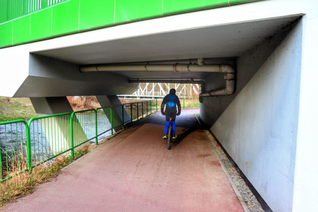 Rowerzysta przejeżdżający pod mostem na ścieżce rowerowej w mieście Wisła
