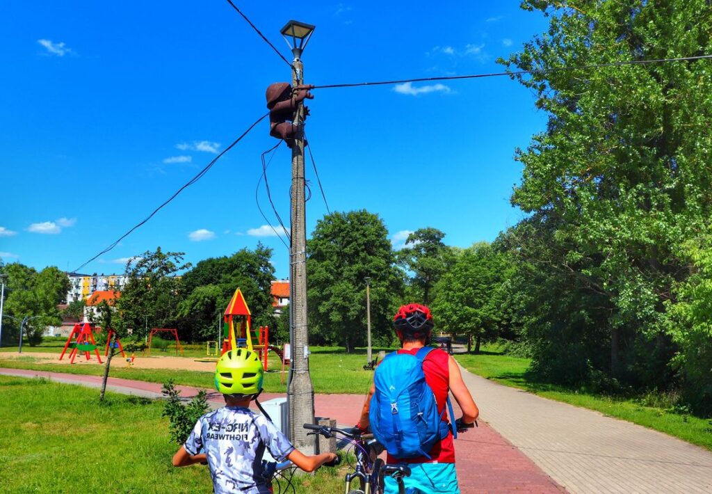 POFAJDOK ORNITOLOG, MIASTO SZCZYTNO, ROWERZYŚCI - DZIECKO Z TATĄ, NIEBIESKIE NIEBO