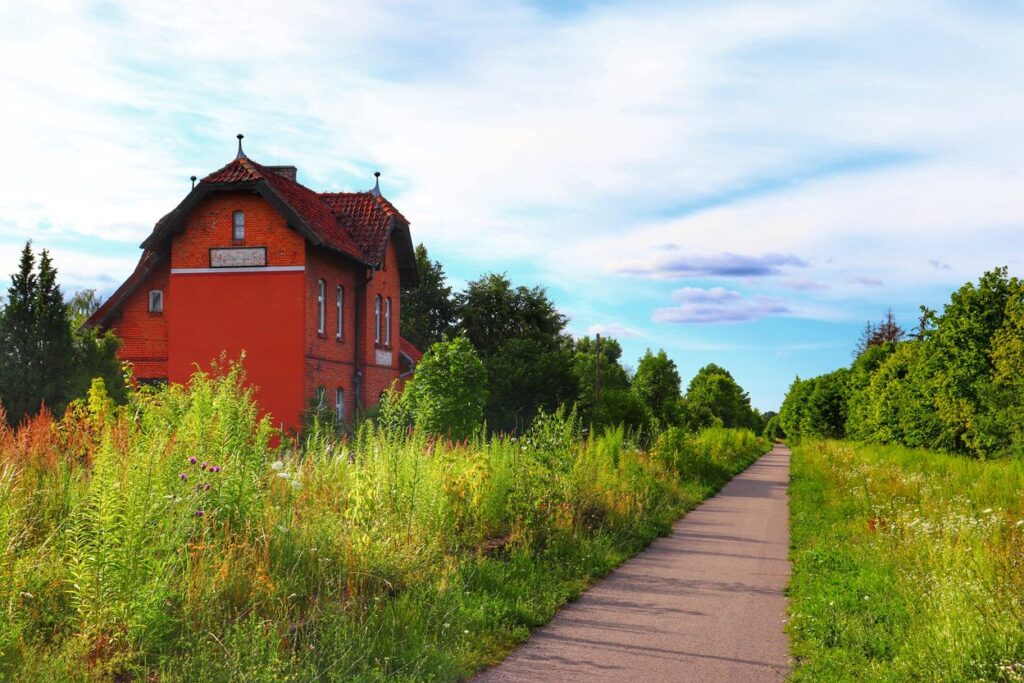 DŹWIERZUTY, budynek dawnej stacji kolejowej, droga asfaltowa, trasa rowerowa Rowerem po kolei na Mazurach