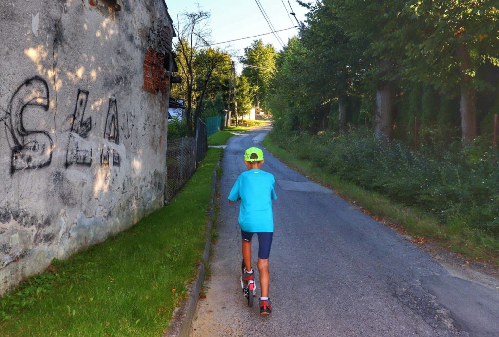 Dziecko na hulajnodze, droga asfaltowa, mur, szlak czarny, Mszana Dolna