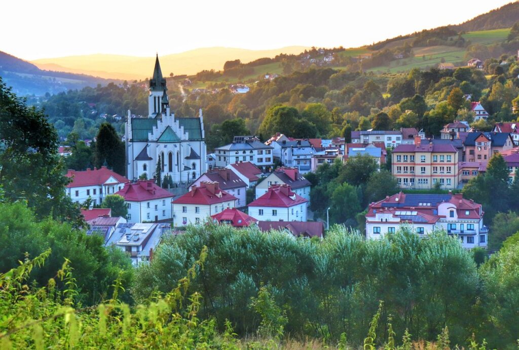 Widok na Mszanę Dolną, zabudowania, kościół ze ścieżki spacerowej na Górę Grunwald, letni wieczór 