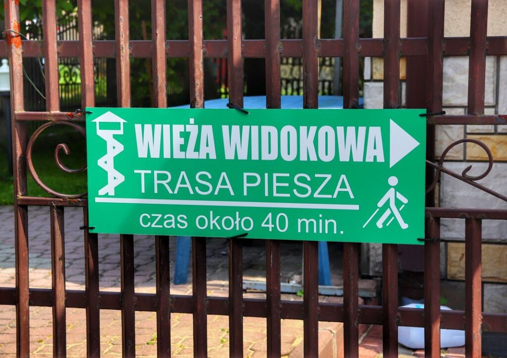 Zielona tabliczka wskazująca kierunek trasy spacerowej na wieżę widokową na Hajdówce, Jordanów