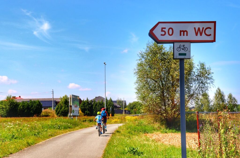 Rowerzyści - dziecko z tatą, szeroka i asfaltowa droga, zielony szlak rowerowy, Meandry Odry