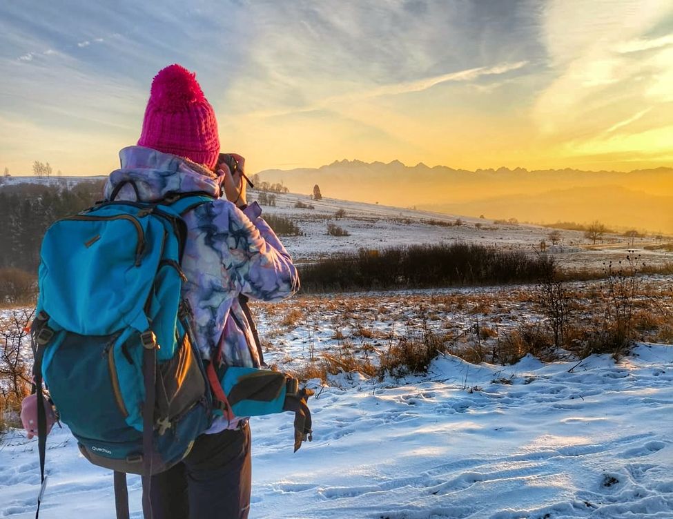 Turystka fotografująca Tatry o zachodzie słońca na szlaku niebieskim. Kluszkowce