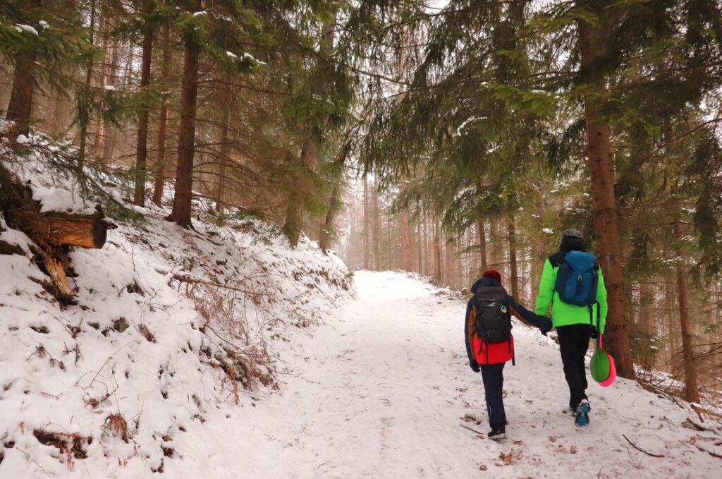 Turysta z dzieckiem, strome i zaśnieżone podejście przez las na żółtym szlaku, Ropiczka