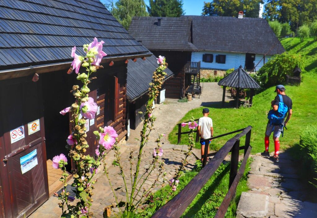 Turysta z dzieckiem zwiedzający Skansen Drewnianego Budownictwa Ludowego w Dobczycach