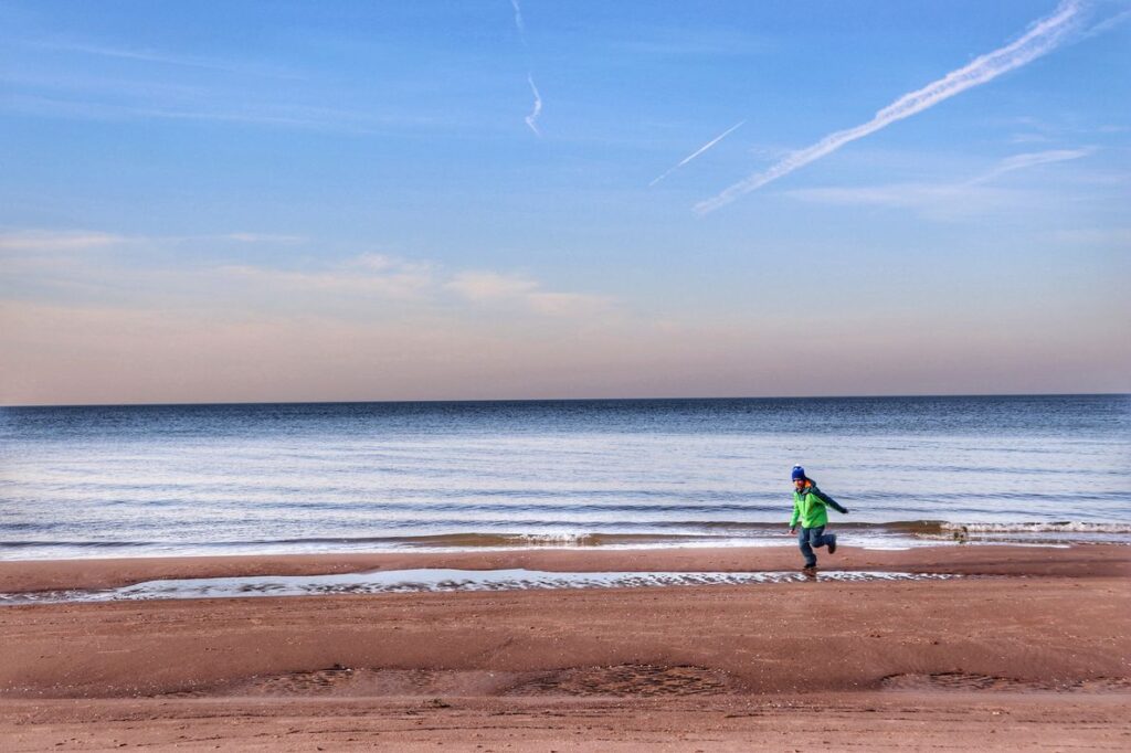 Dziecko biegnące po plaży w Trzęsaczu