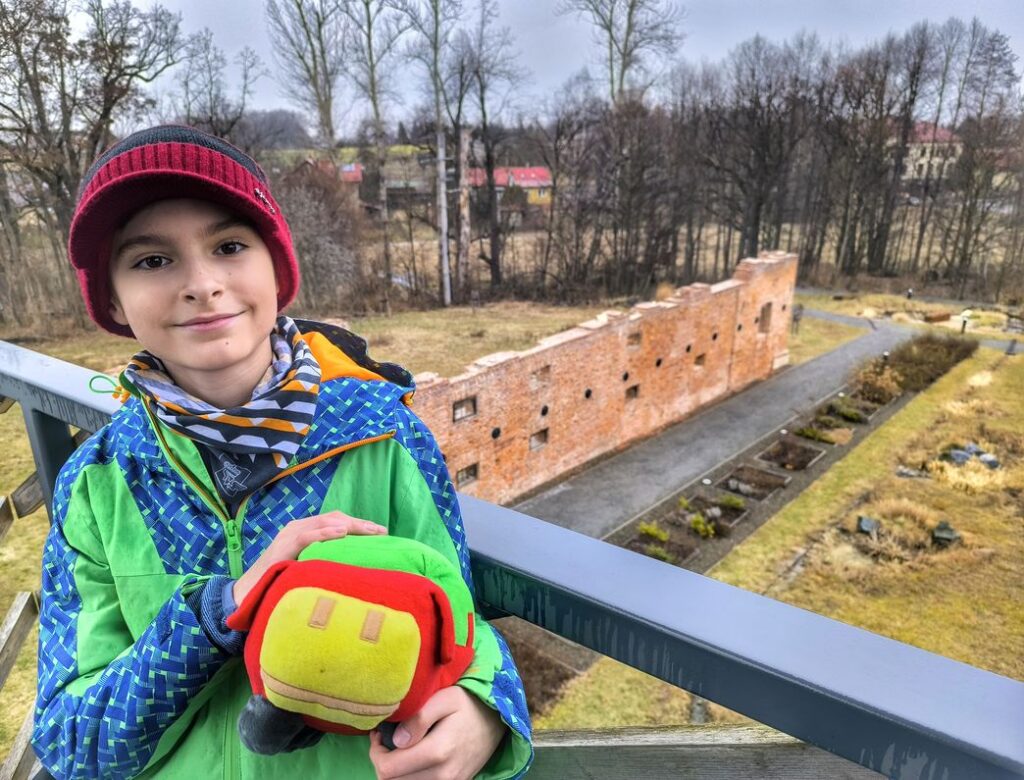 Uśmiechnięte dziecko na wieży widokowej w Czechowicach, w tle Ruiny zamku Wilczków