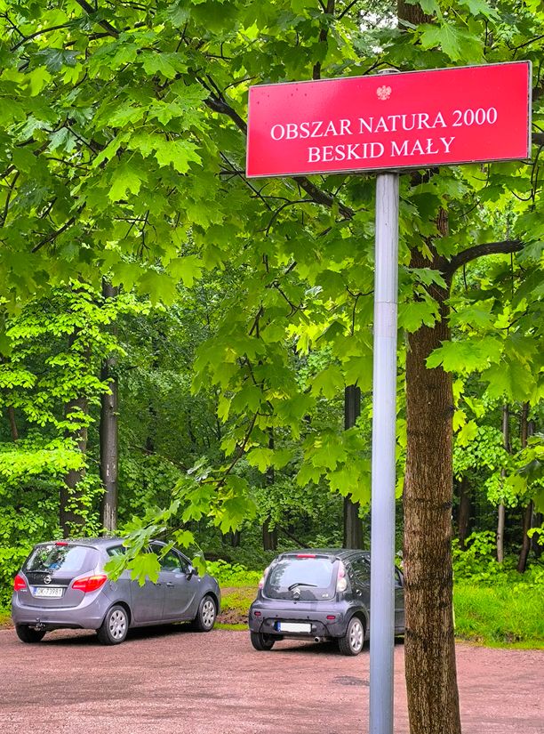 Czerwona tabliczka OBSZAR NATURA 2000 BESKID MAŁY przy parkingu przy niebieskim szlaku w Lipniku
