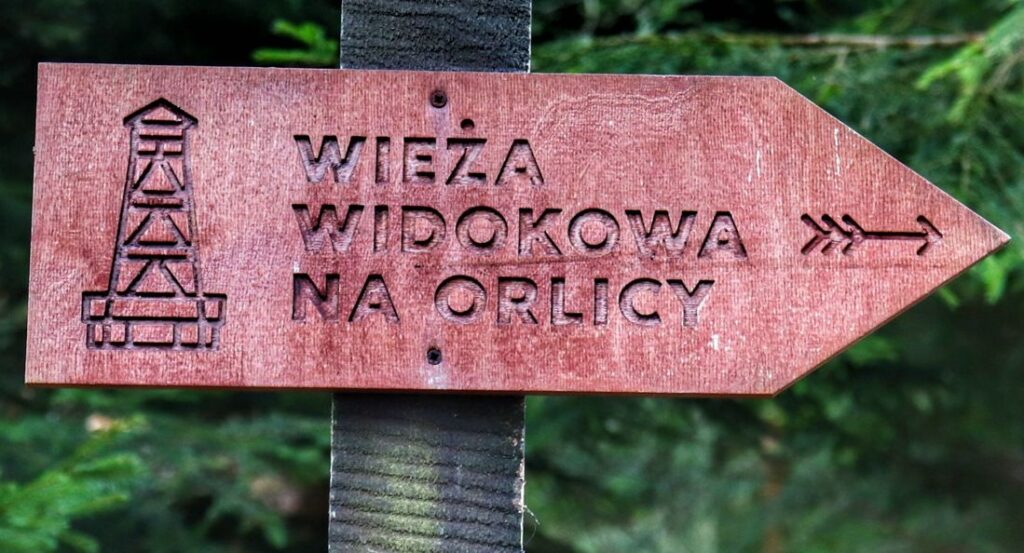 Tabliczka w kształcie strzałki z napisem WIEŻA WIDOKOWA NA ORLICY