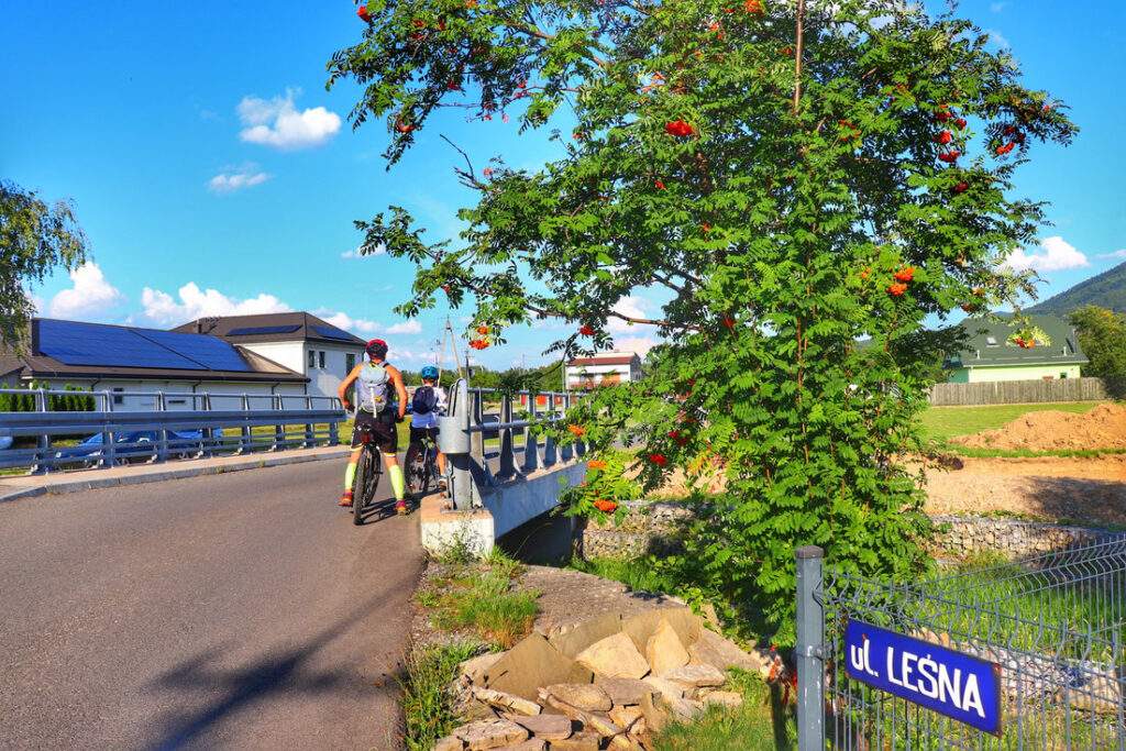 Rowerzysta z dzieckiem, ulica Leśna, most- Kobiernice Małe