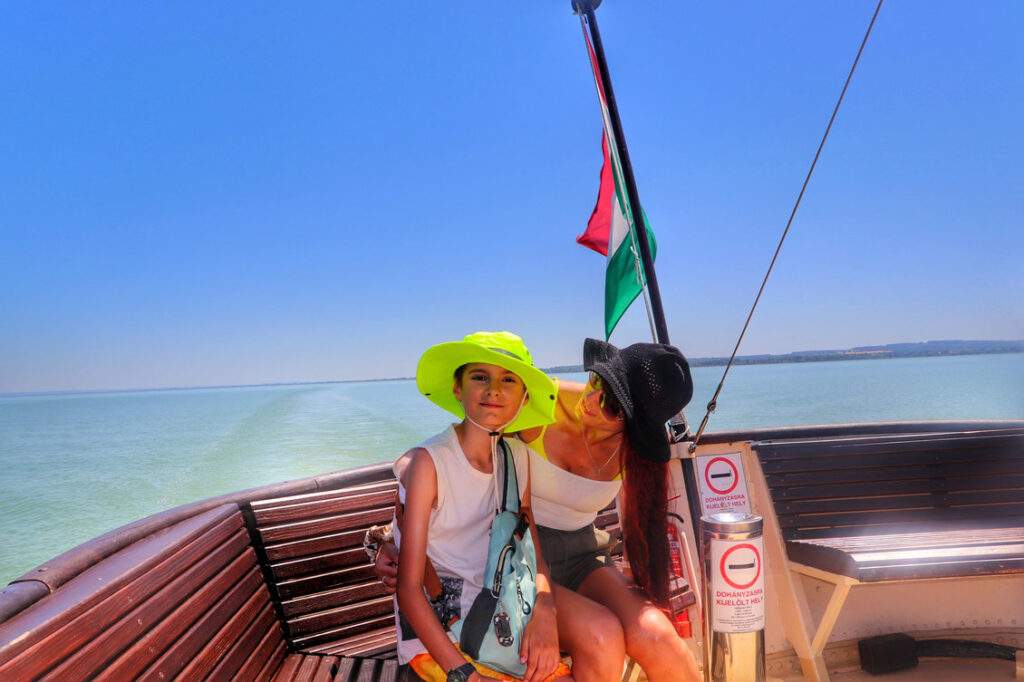 Mama z dzieckiem na rejsie statkiem w mieście Keszthely po jeziorze Balaton, w tle węgierska flaga