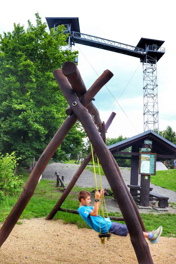 Dziecko na drewnianej huśtawce, w tle wieża widokowa - Graniczny Wierch, Czechy