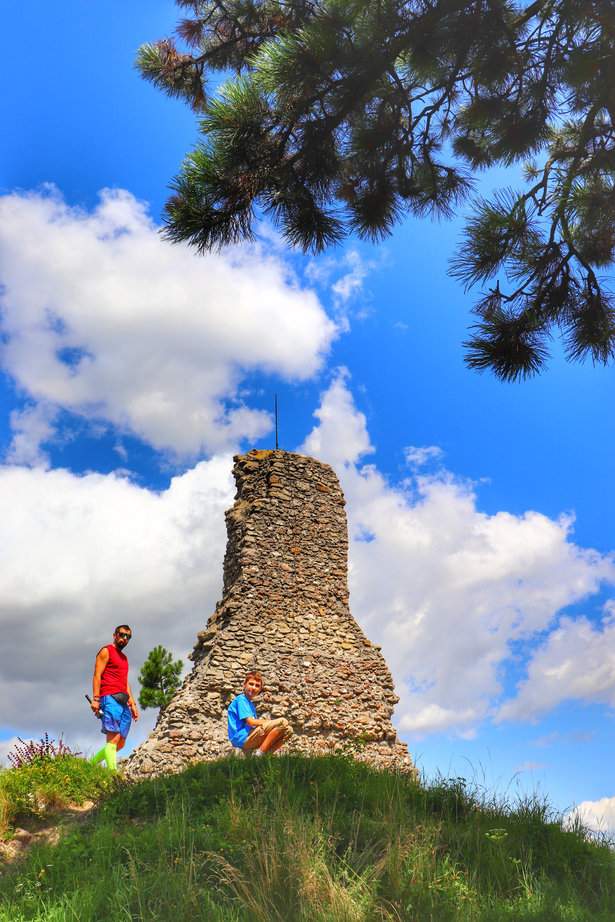 Mężczyzna z dzieckiem zwiedzający ruiny zamku w czeskim Starým Jičínie, pod błękitnym niebem z białymi chmurami