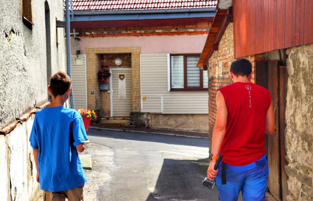 Turysta z dzieckiem przechadzający się wąską uliczką między zabudowaniami w Starým Jičínie w Czechach