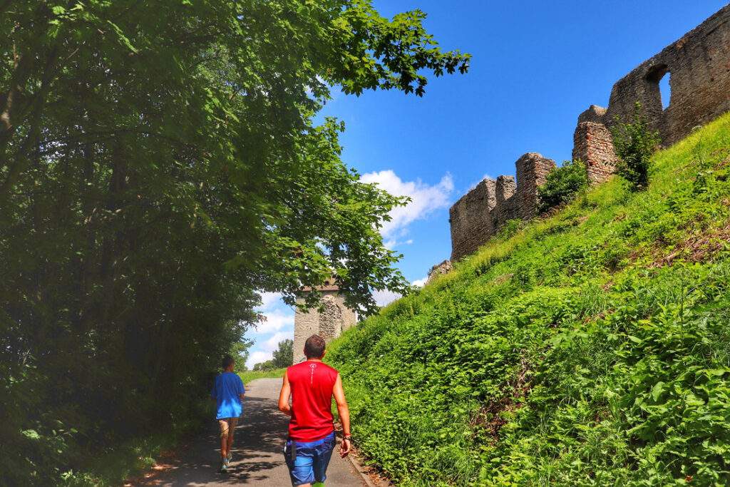 Turysta z dzieckiem, szeroka, asfaltowa droga, ruiny zamku Stary Jiczyn