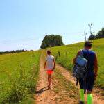 Turysta z dzieckiem wędrujący drogą między łąkami