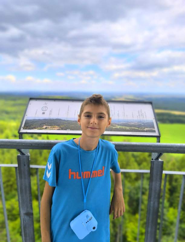 Uśmiechnięte dziecko na wieży widokowej na Granicznym Wierchu w Górach Opawskich, tablica z panoramą