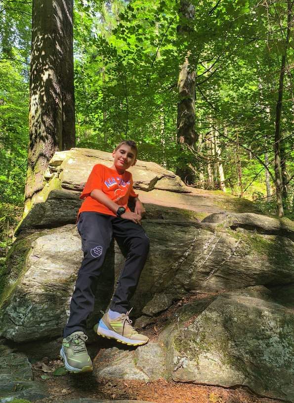 Uśmiechnięte dziecko odpoczywające na skale, las