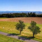 Widok rozpościerający się z wieży widokowej Pohoř - Olšová - Odry, droga, drzewa, pola, w tle krajobraz górski