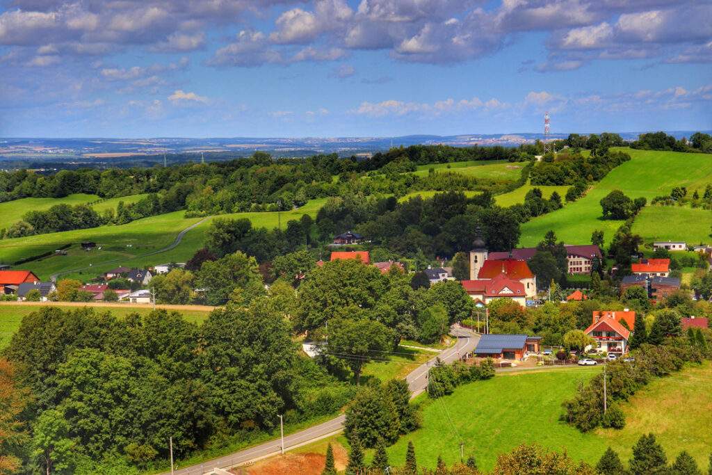 Widok rozciągający się na okolicę z wieży widokowej Okrouhlá - letni krajobraz i błękitne niebo