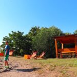 Dziecko zmierzające w stronę ruin zamku Lichnice, w pobliżu wiata wypoczynkowa i leżaki