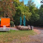 Budka gastronomiczna z stołami, ławkami i parasolkami przy parkingu przy niebieskim szlaku prowadzącym do ruin zamku Vikštejn w Radkovie