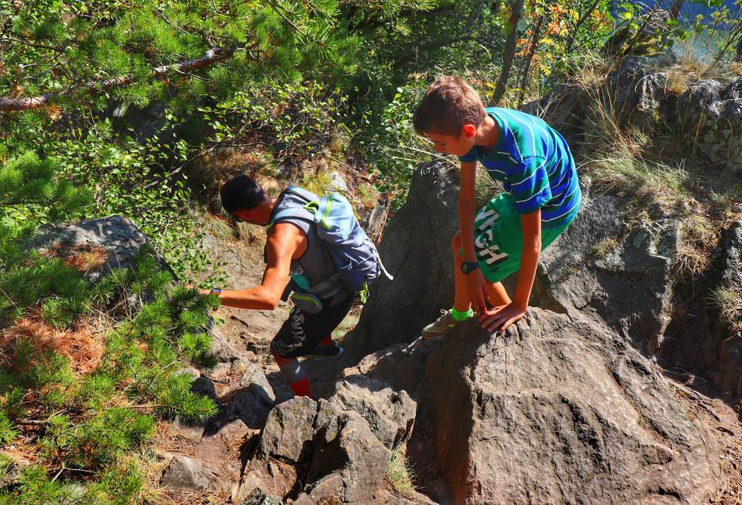 Turyści - mężczyzna z dzieckiem schodzący po skałach ze skalnego punktu widokowego Mały Oheb w Górach Żelaznych w Czechach